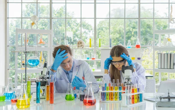 Stressed unsuccessful western scientists couple working failed on test tube to analysis and develop vaccine of covid-19 virus in lab or laboratory in technology medical, chemistry, healthcare.
