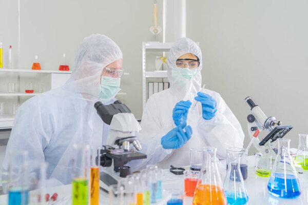Пара западных ученых работает над пробиркой для анализа и разработки вакцины вируса ковид-19 в лаборатории или лаборатории в области технологий медицины, химии, здравоохранения, исследований. Экспериментальные науки.