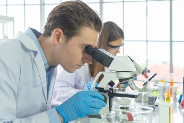 Batılı bir bilim adamı çifti laboratuvar, tıbbi, kimya, sağlık ve araştırma laboratuarlarında kovid-19 virüsü aşısı geliştirmek ve analiz etmek için test tüpü üzerinde çalışıyor. Deneysel bilim.