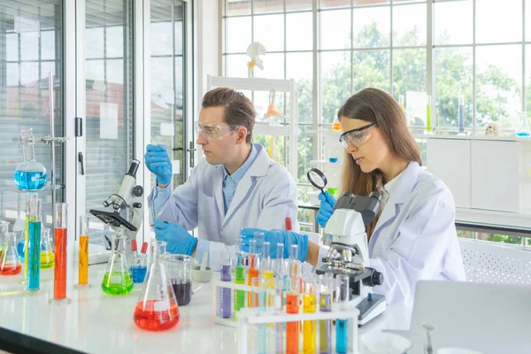 Batılı bir bilim adamı çifti laboratuvar, tıbbi, kimya, sağlık ve araştırma laboratuarlarında kovid-19 virüsü aşısı geliştirmek ve analiz etmek için test tüpü üzerinde çalışıyor. Deneysel bilim.