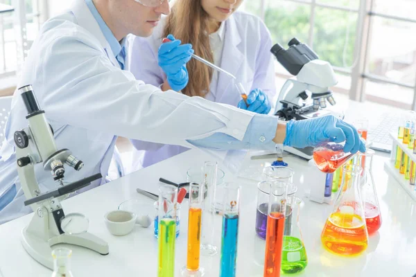 A western scientists couple working on test tube to analysis and develop vaccine of covid-19 virus in lab or laboratory in technology medical, chemistry, healthcare, research. Experimental science.