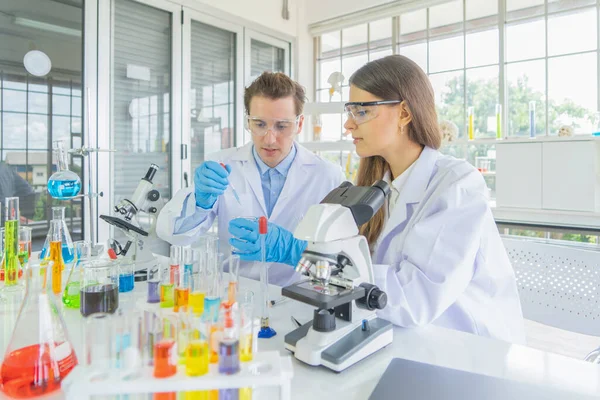 Batılı bir bilim adamı çifti laboratuvar, tıbbi, kimya, sağlık ve araştırma laboratuarlarında kovid-19 virüsü aşısı geliştirmek ve analiz etmek için test tüpü üzerinde çalışıyor. Deneysel bilim.