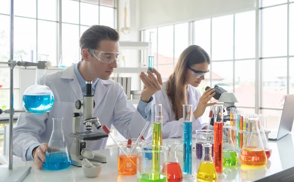 Batılı bir bilim adamı çifti laboratuvar, tıbbi, kimya, sağlık ve araştırma laboratuarlarında kovid-19 virüsü aşısı geliştirmek ve analiz etmek için test tüpü üzerinde çalışıyor. Deneysel bilim.