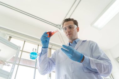 Batılı bir bilim adamı laboratuvar, tıbbi, kimya, sağlık ve araştırma laboratuvarında kovid-19 virüsü aşısını analiz etmek ve geliştirmek için test tüpü üzerinde çalışıyor. Deneysel bilim.