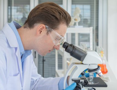 Batılı bir bilim adamı laboratuvar, tıbbi, kimya, sağlık ve araştırma laboratuvarında kovid-19 virüsü aşısını analiz etmek ve geliştirmek için test tüpü üzerinde çalışıyor. Deneysel bilim.