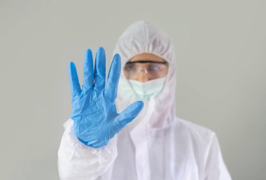 Batılı bilim adamı veya doktor kadın portresi Covid-19 takım elbisesi ve maskesiyle hastanede tıbbi sağlık hizmetleri ve korona virüsü salgını konseptinde gri arka plan üzerinde çalışıyor..