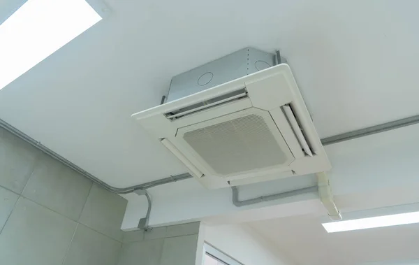 オフィスビルシステムの仕事で現代的な白い天井に取り付けられたカセットタイプのエアコン 換気圧縮機 — ストック写真
