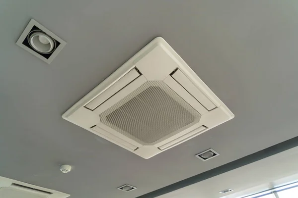 Modern white ceiling mounted cassette type air conditioner in office building system work. Ventilation compressor.