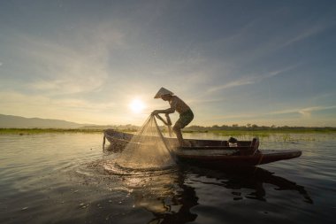 Siluet Balıkçısı, Tayland 'da Asya' da sabah saatlerinde, doğa gölünde ya da nehirde tatlı su balığı yakalamak için ağ atıyor ya da atıyordu. İnsanlar.