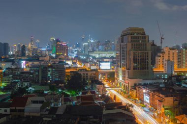 Bangkok 'ta kavşakta ya da cadde üzerindeki köprüde giden arabaların hava görüntüsü. Tayland. Asya 'daki şehir. Geceleri binalar.