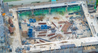 İnşaat işçileri altında vinç ve kazıcılarla çalışan yoğun endüstriyel hava manzarası. Çelik kaplı döşeme öncesi beton döşeme manzarası. Yüksek binalı mimari bina geliştirme.