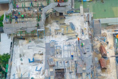 İnşaat işçileri altında vinç ve kazıcılarla çalışan yoğun endüstriyel hava manzarası. Çelik kaplı döşeme öncesi beton döşeme manzarası. Yüksek binalı mimari bina geliştirme.