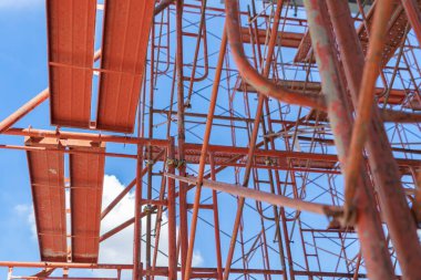 İskele iskelesi. İnşaat sahasının altında vinçlerle dolu sanayi bölgesinde kafes direği, kablo ya da direkler. Çelik ya da metal yapı. Geliştirme mimari binası.