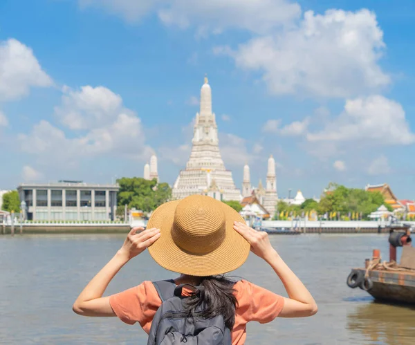 Asian woman, a tourist people, travelling in Temple of Dawn or Wat Arun and Chao Phraya River, Bangkok, Thailand. Urban old town city in holiday vacation. Lifestyle activity concept.