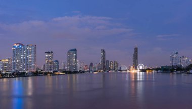 Bangkok, Tayland 'da Chao Phraya Nehri' nin yanında dönme dolap. Finans bölgesi ve gökdelen binaları. Şehir merkezi geceleri gökyüzü.