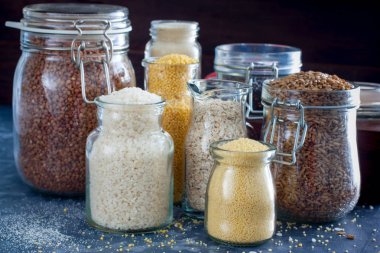 Bir tabloda, yatay cam kavanozlara çeşitli hububat ürünleri