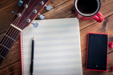 Gitar, sade kahve, smartphone ve ahşap bir masa üstü temiz Not kitap görünümü, yatay, alanı, müzik kavramı kopya