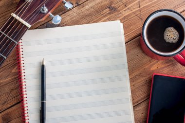 Gitar, sade kahve, smartphone ve ahşap bir masa üstü temiz Not kitap görünümü, yatay, alanı, müzik kavramı kopya