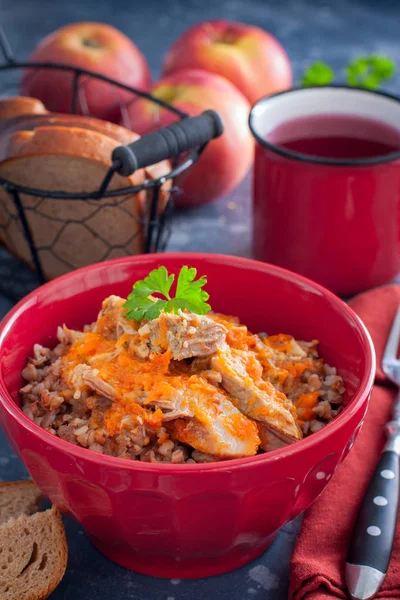 Buckwheat porridge with meat in a red bowl, selective focus