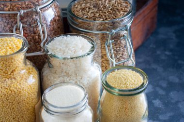 Bir tabloda, yatay cam kavanozlara çeşitli hububat ürünleri