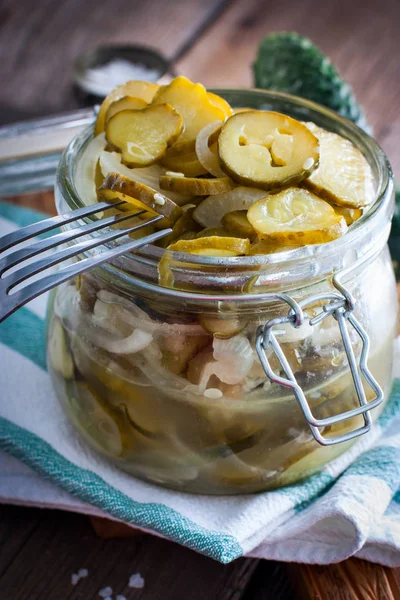 salad from pickled cucumbers with onions in a glass jar, blanks for the winter, selective focus