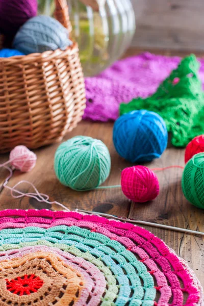 Multicolored yarn balls in a straw basket on a wooden table Stock