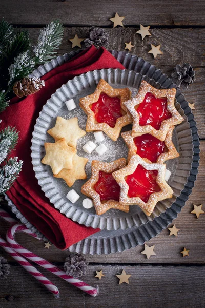 Christmas cookies. Linzer cookies with raspberry jam on green table background. Traditional Austrian biscuits filled. Top view and copy space