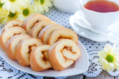 Bisküvi reçel çay ile bir beyaz masaya yatay rulo.