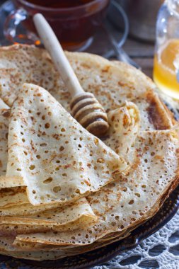 Ev yapımı ince krep yerken üzerine bal, seçici odak ile ahşap bir masa