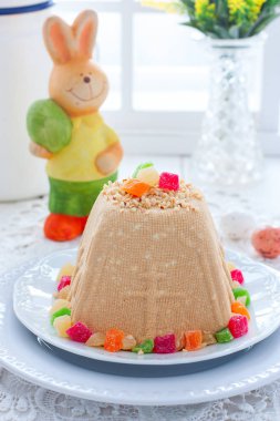 Geleneksel lor Paskalya ile yoğunlaştırılmış süt, fındık ve şekerlenmiş meyve bir festival ışık dekor, seçici odak içinde beyaz bir plaka üzerinde