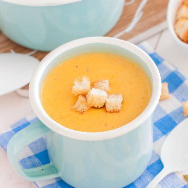 Mavi bir emaye kupa beyaz ekmek croutons, kare balkabağı çorbası