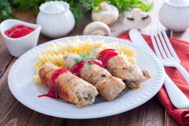 Küçük domuz eti rulo - mantarlı makarna ve ketçap, yatay ile beyaz bir plaka üzerinde domuz parmak
