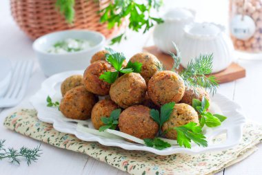 Nohut falafel yatay bir beyaz masaya taze otlar ile