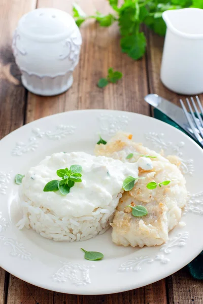 Bacalhau frito, cozido com arroz e molho de creme em um prato branco, foco seletivo — Fotografia de Stock