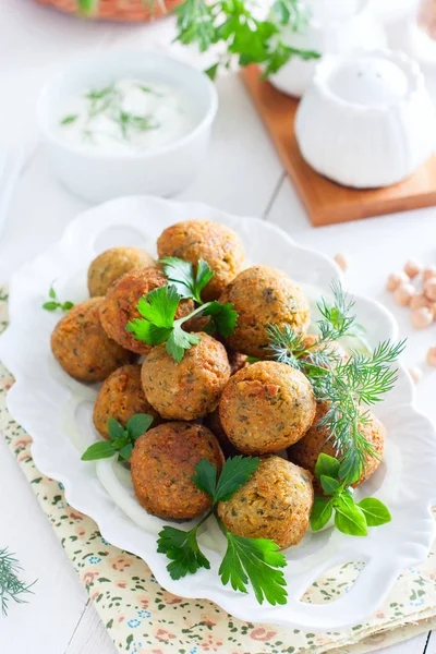 Falafel de grão de bico com ervas frescas em uma placa branca, foco seletivo — Fotografia de Stock