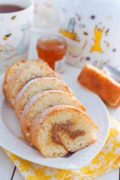 Rolo de biscoito com leite condensado fervido em uma placa branca, foco seletivo — Fotografia de Stock