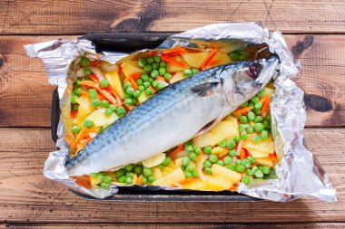 Sebzeli - patates, havuç, soğan, yeşil bezelye pişirme, en iyi görünüm için hazırlanan bir tabak içinde ham uskumru