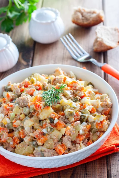 Ensalada rusa en español con atún enlatado en un plato blanco sobre una mesa de madera, horizontal — Foto de Stock