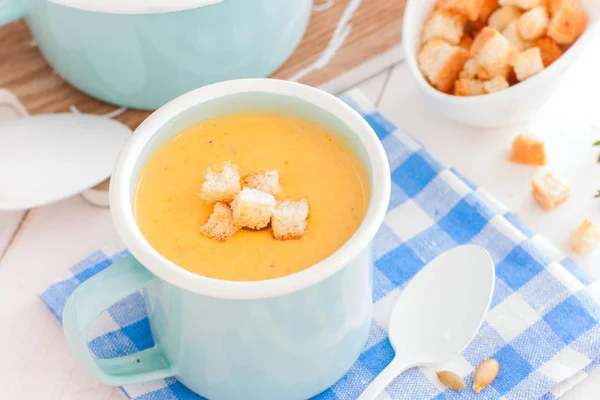 Pumpkin cream soup in a blue enamelled mug with crackers, horizontal — Stock Photo, Image