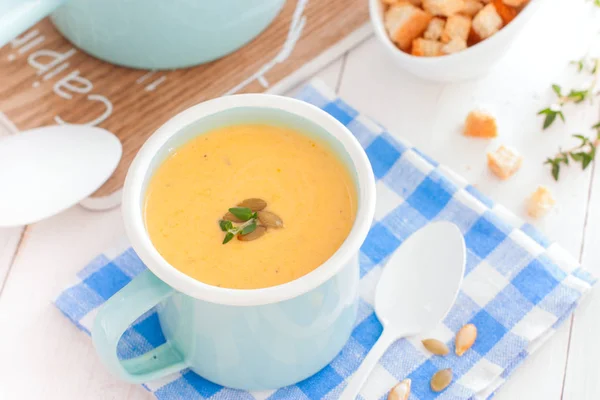 Pumpkin soup in blue enamelled mug with pumpkin seeds, horizontal — Stock Photo, Image