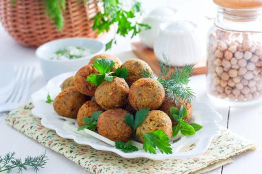 Nohut falafel yatay bir beyaz masaya taze otlar ile