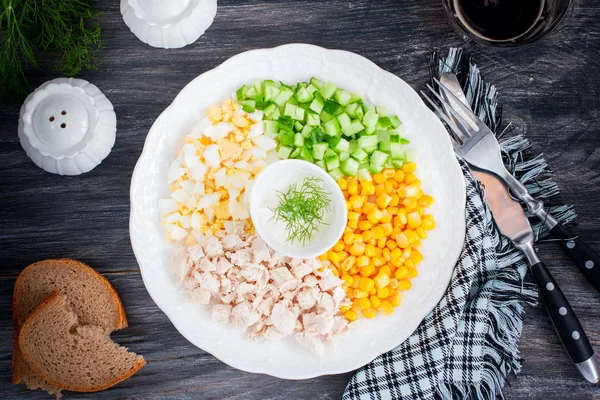 Кукурузный салат, огурец, яйцо, курица на белой тарелке на черном столе, вид сверху, горизонтальный — стоковое фото