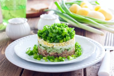 Konserve balık ve yatay bir beyaz tabakta yeşil soğan salatası