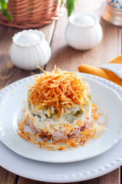 Insalata con funghi, cetrioli e pollo, guarnita con torta di patate fritte su un piatto bianco, fuoco selettivo — Foto Stock