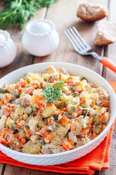 Russische salade in het Spaans met ingeblikte tonijn op een witte plaat op een houten tafel, horizontale — Stockfoto