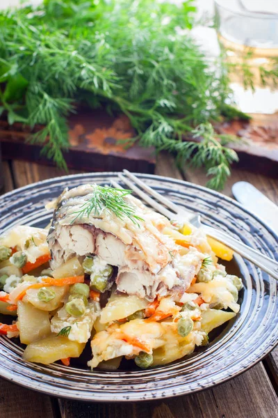 Запечённая макрель с овощами - картофель, морковь, лук, зеленый горошек в тарелке, избирательный фокус — стоковое фото