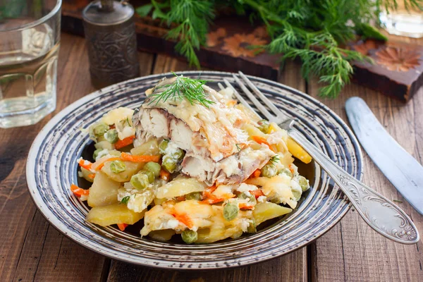 Запечённая макрель с овощами - картофель, морковь, лук, зеленый горошек в тарелке, избирательный фокус — стоковое фото