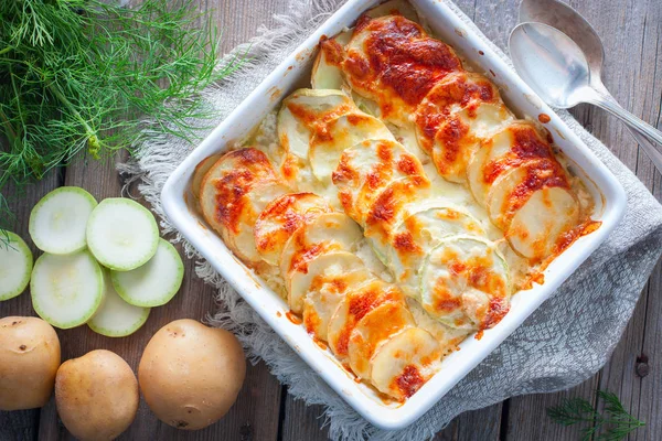 Gratinado de abobrinhas e batatas jovens em uma mesa de madeira, vista superior — Fotografia de Stock