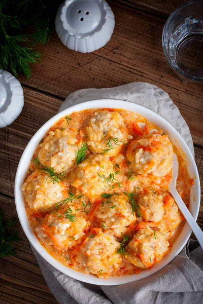 Frikadellen mit Reis in Tomaten-Saure-Sahne-Sauce auf einem Holztisch, Draufsicht, selektiver Fokus — Stockfoto