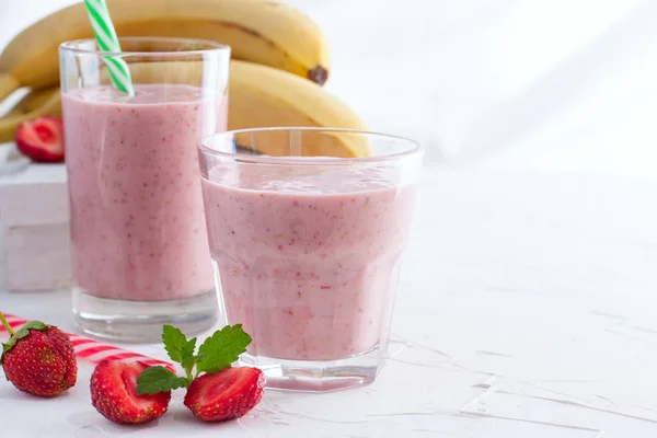 Smoothies of fresh strawberries and bananas in glass glasses on a white table, copy space — Stock Photo, Image